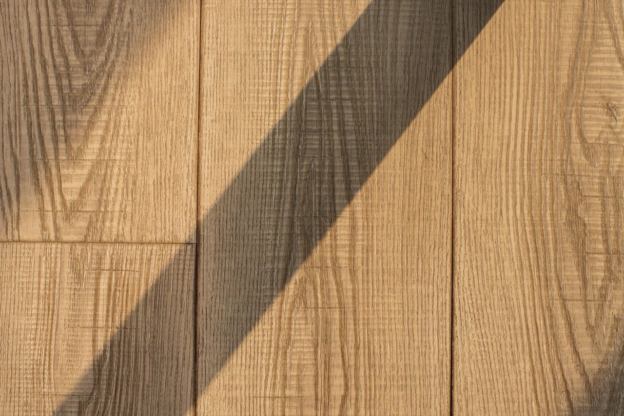 Oak floorboards with a diagonal shadow falling across the grain