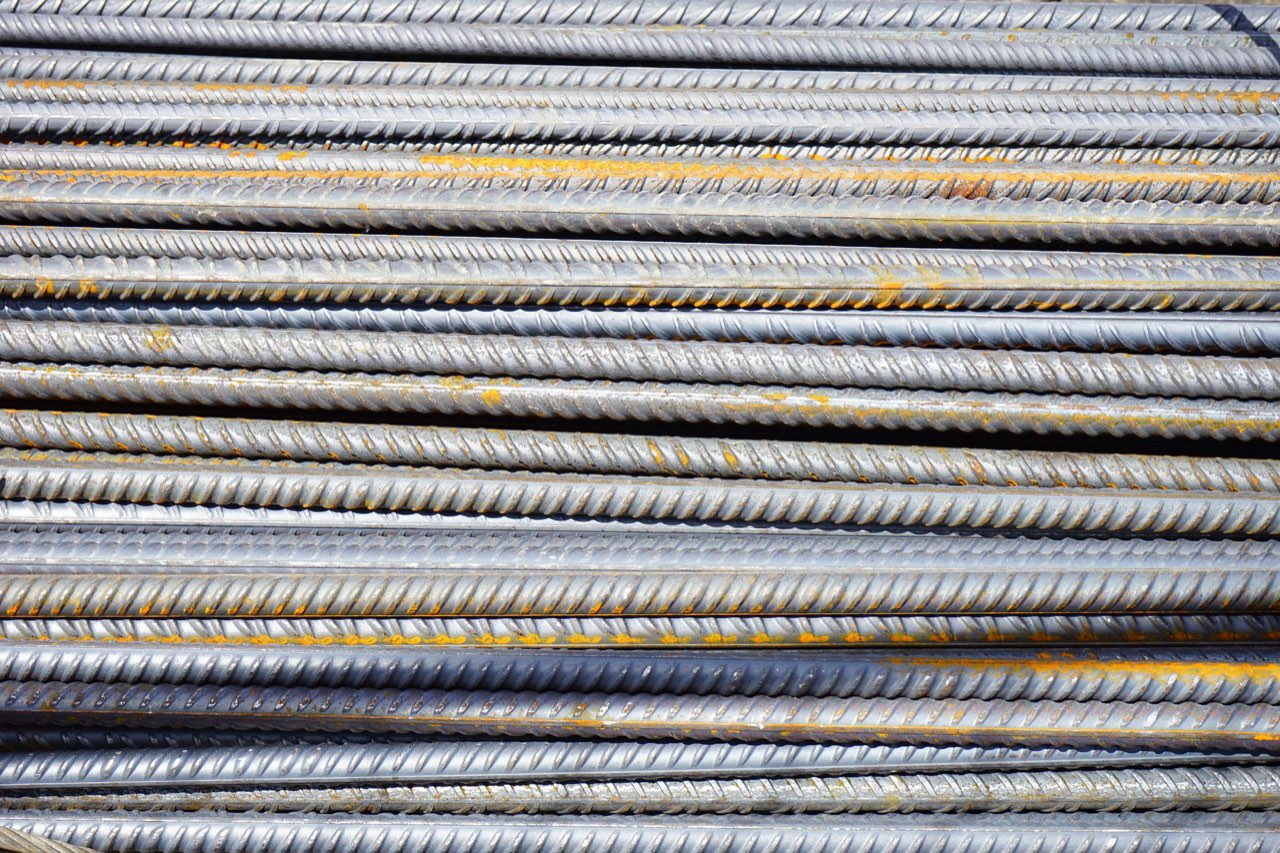 Ribbed steel reinforcing bars stacked side by side, grey with streaks of surface rust