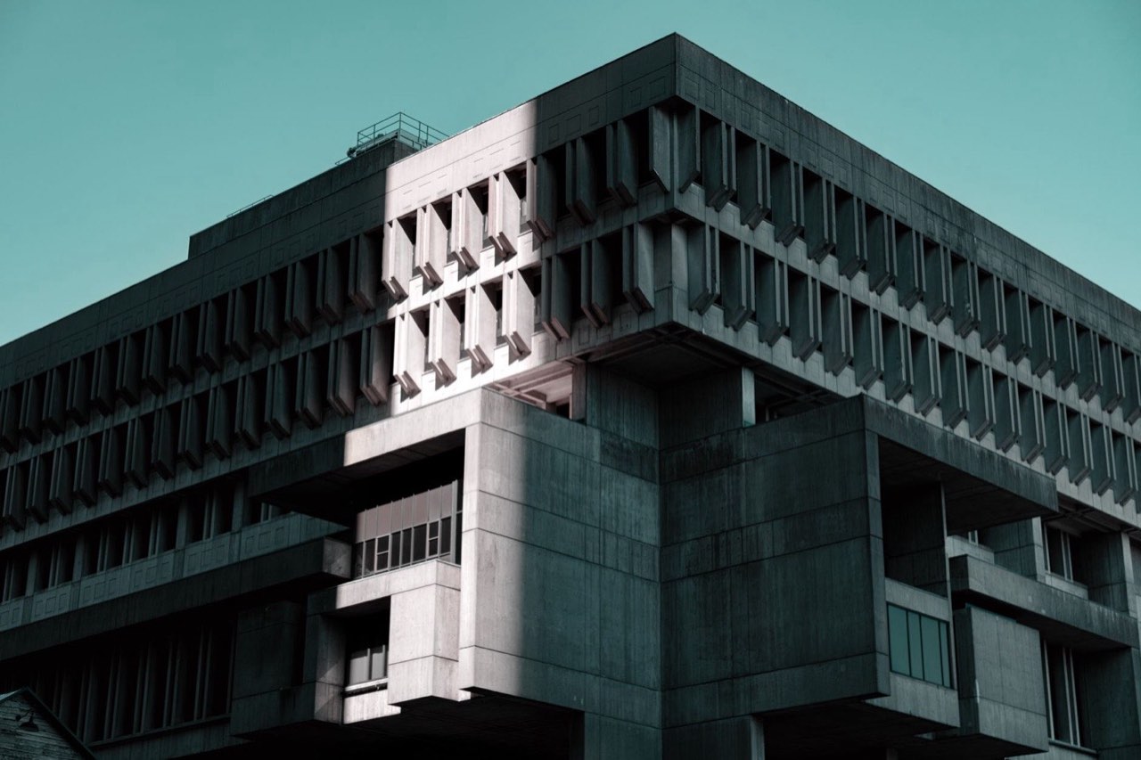 The corner of a concrete brutalist building, one bay lit by low sun