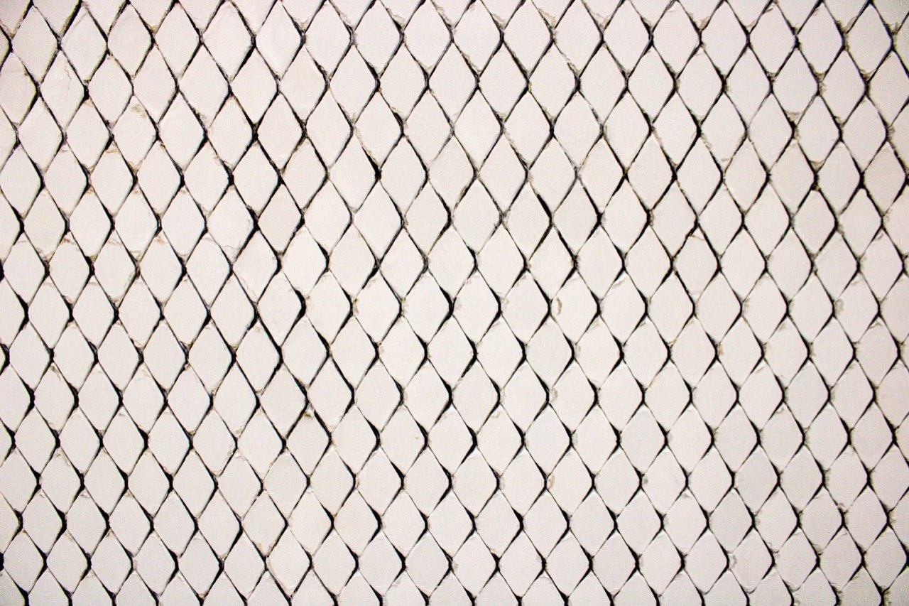 A wall of small white diamond-shaped tiles with dark grout lines between them